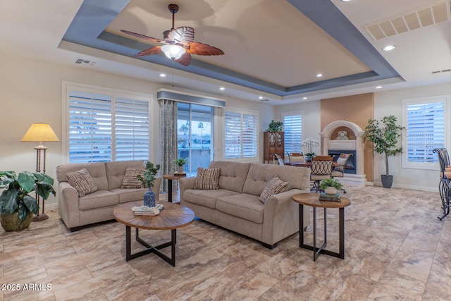 living room featuring a raised ceiling and ceiling fan