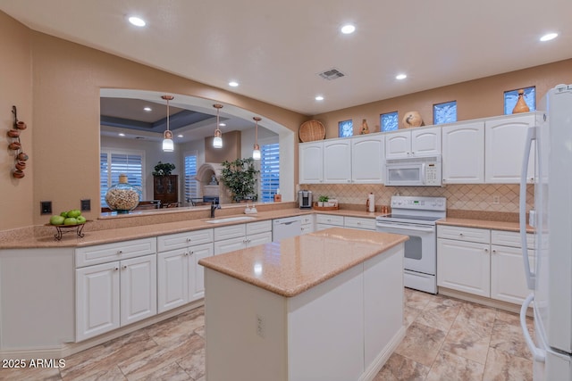 kitchen featuring white appliances, white cabinets, hanging light fixtures, and kitchen peninsula