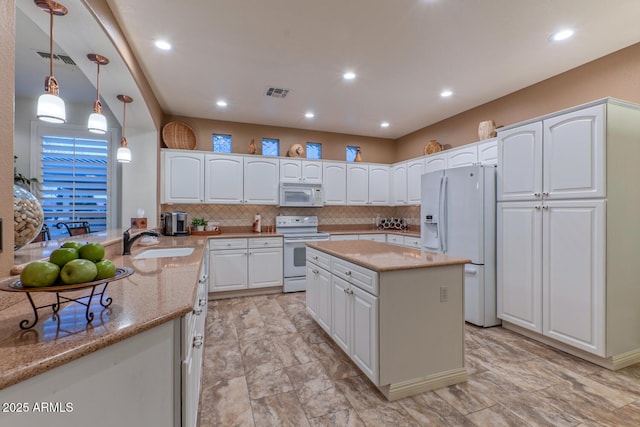 kitchen with white appliances, kitchen peninsula, decorative light fixtures, white cabinets, and sink