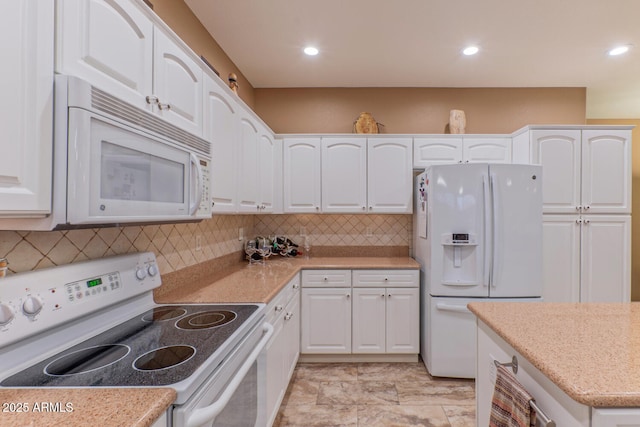 kitchen with white appliances, decorative backsplash, and white cabinets