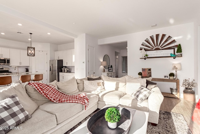 living area with light wood-style flooring, visible vents, and recessed lighting