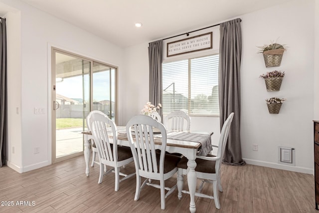 dining room featuring baseboards, a healthy amount of sunlight, and light wood finished floors