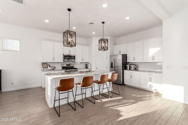 kitchen with tasteful backsplash, light wood-style flooring, a breakfast bar area, stainless steel appliances, and a sink