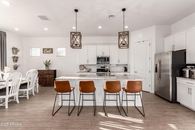 kitchen with stainless steel appliances, visible vents, a sink, and a kitchen bar