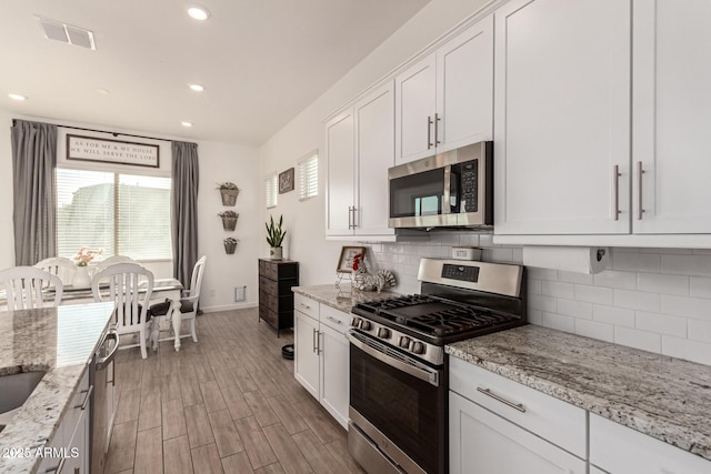 kitchen featuring appliances with stainless steel finishes, visible vents, light wood finished floors, and white cabinetry