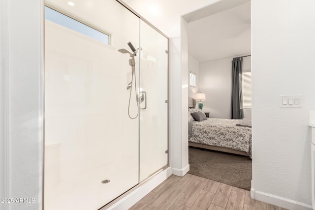 ensuite bathroom featuring a stall shower, baseboards, ensuite bath, and wood finished floors