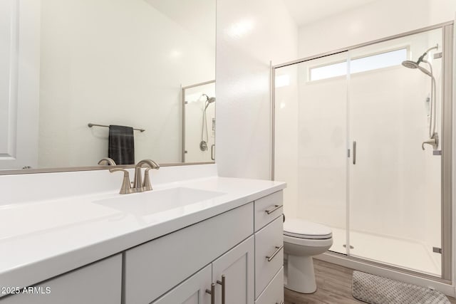 full bath featuring a stall shower, vanity, toilet, and wood finished floors