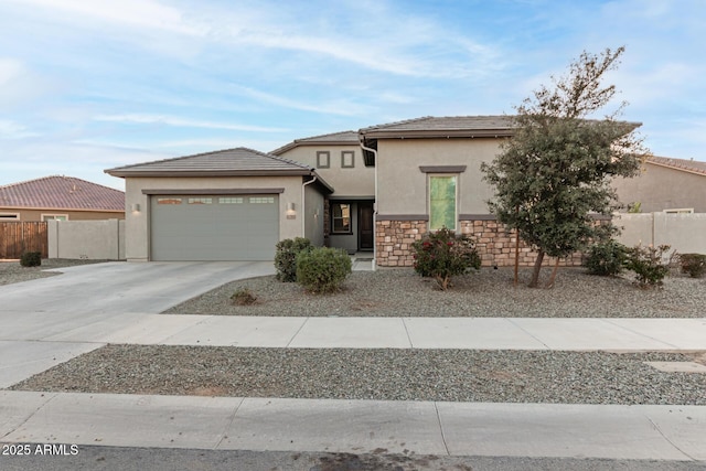 prairie-style home featuring a garage, fence, driveway, stone siding, and stucco siding