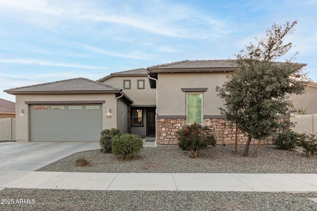 view of front of home with stucco siding, an attached garage, fence, stone siding, and driveway