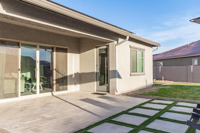 rear view of house with a yard, fence, a patio, and stucco siding