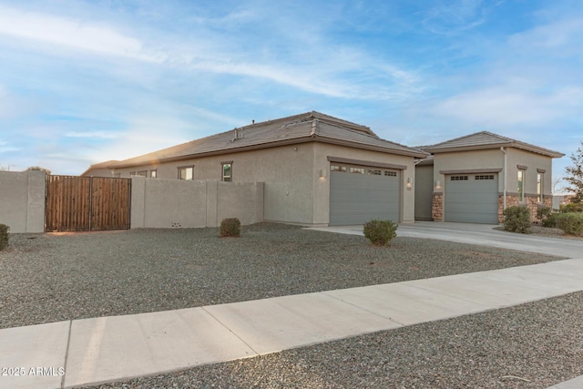 view of property exterior with a garage, driveway, fence, and stucco siding