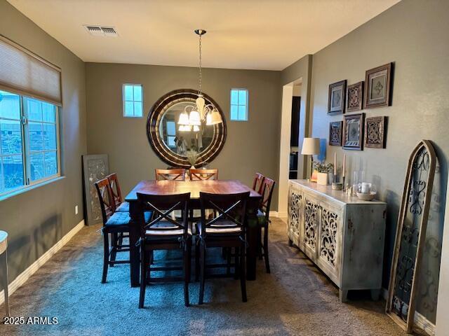 carpeted dining space with an inviting chandelier and a healthy amount of sunlight