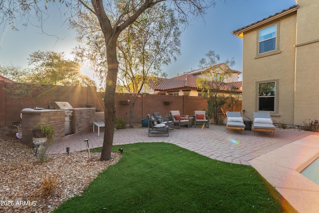 yard at dusk featuring an outdoor kitchen, an outdoor living space, and a patio