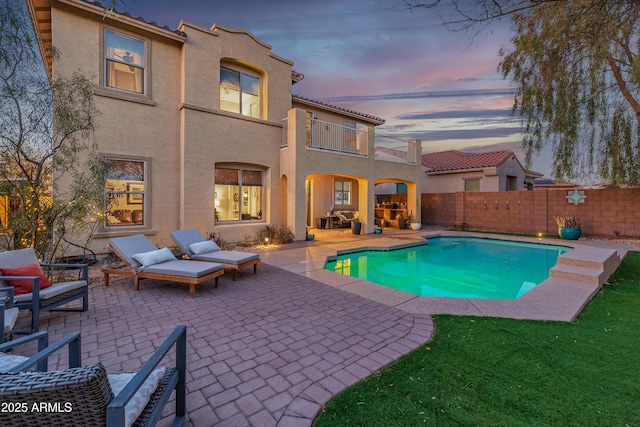 pool at dusk with a patio area