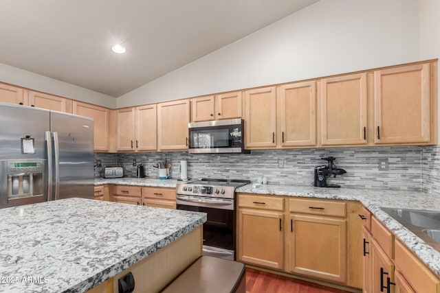 kitchen featuring appliances with stainless steel finishes, lofted ceiling, light brown cabinets, backsplash, and wood finished floors