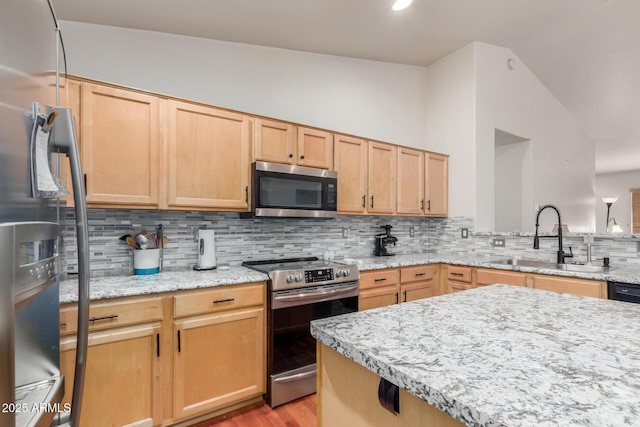 kitchen with stainless steel appliances, a sink, light brown cabinetry, vaulted ceiling, and decorative backsplash