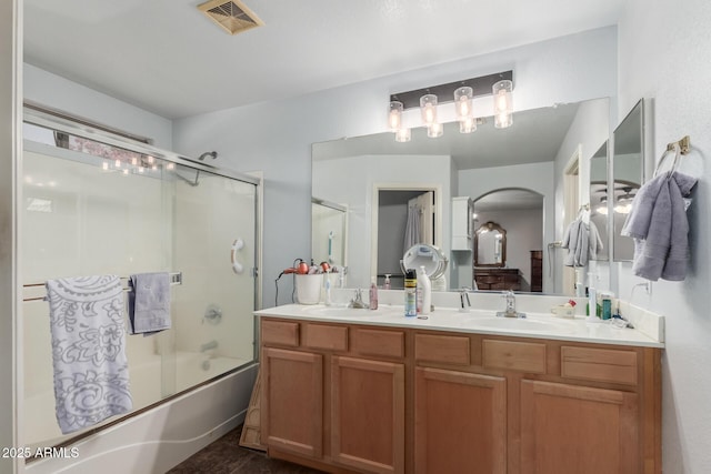 bathroom with double vanity and shower / bath combination with glass door