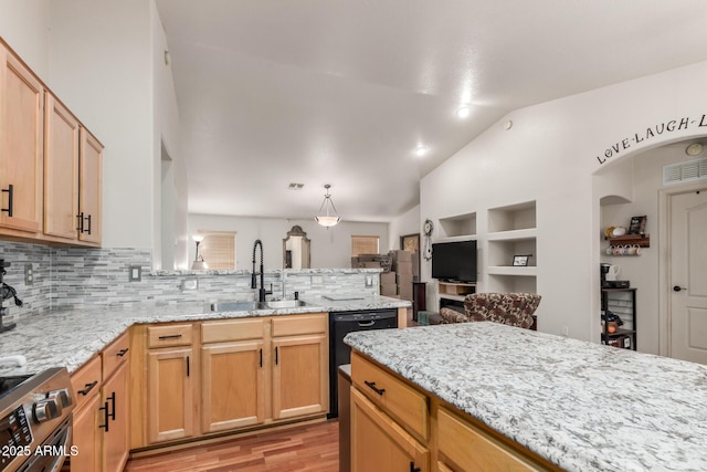 kitchen featuring gas range, a sink, decorative backsplash, vaulted ceiling, and a peninsula