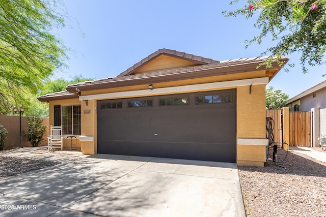 view of front of property with concrete driveway, fence, stucco siding, an attached garage, and a tiled roof