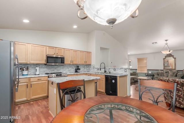 kitchen with stainless steel appliances, a sink, vaulted ceiling, light wood-style flooring, and light brown cabinetry