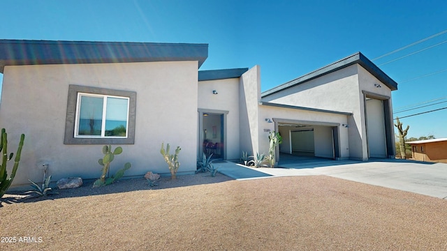 view of front of home with concrete driveway, an attached garage, and stucco siding