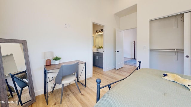 bedroom with light wood-style floors, a closet, baseboards, and ensuite bathroom