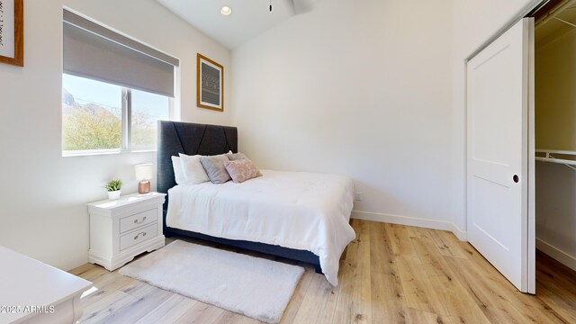 bedroom featuring light wood-type flooring, baseboards, and vaulted ceiling