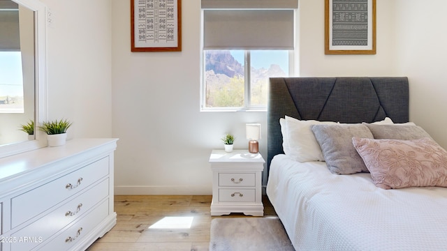 bedroom featuring light wood finished floors and baseboards