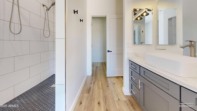 full bath with wood finished floors, tiled shower, and vanity