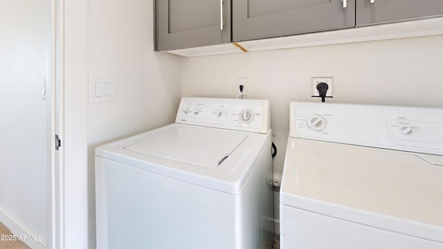 clothes washing area featuring cabinet space and washer and clothes dryer