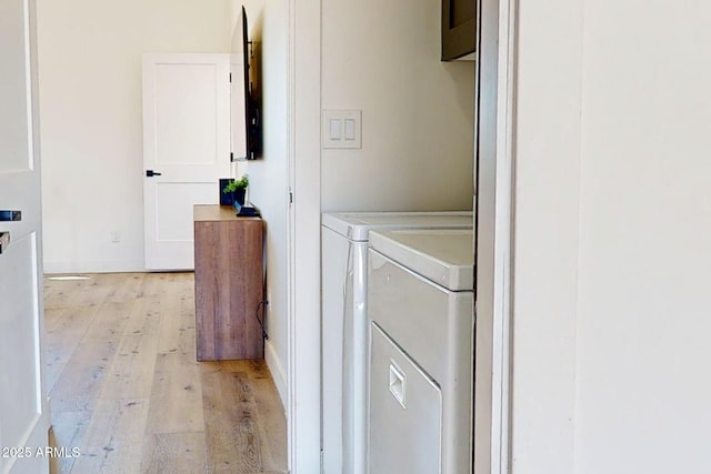 clothes washing area with independent washer and dryer and light wood-style flooring