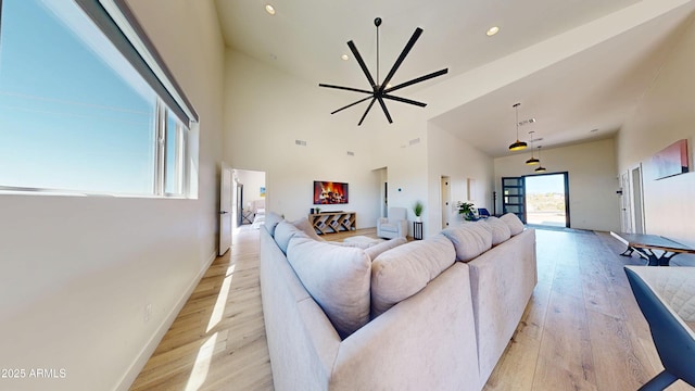living room featuring light wood-style flooring, high vaulted ceiling, recessed lighting, and baseboards