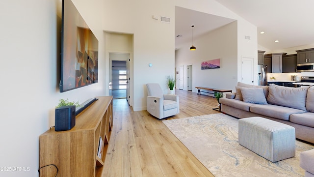 living room featuring light wood-style floors, high vaulted ceiling, and recessed lighting