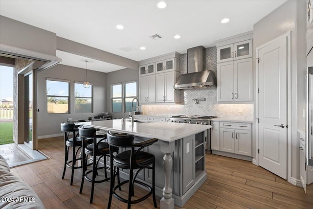 kitchen featuring wall chimney exhaust hood, white cabinetry, dark wood-type flooring, and an island with sink