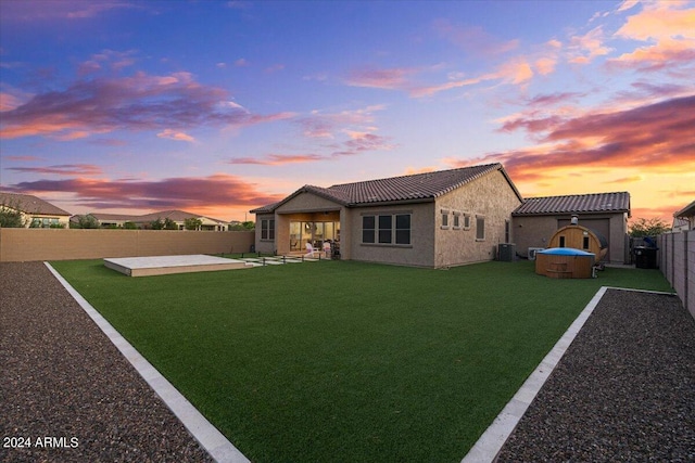 view of front facade with a lawn, a jacuzzi, a patio area, and central AC