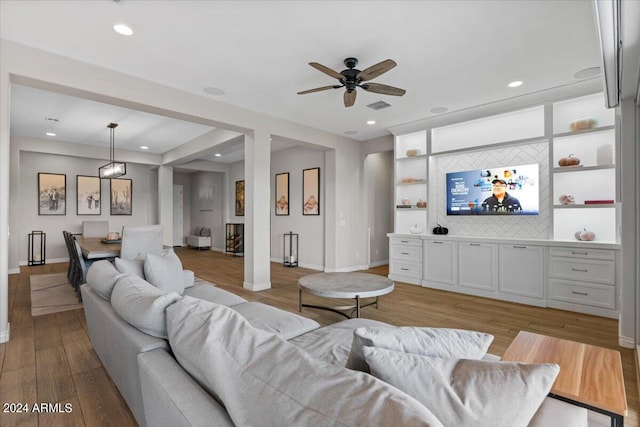 living room with light wood-type flooring, ceiling fan, and built in features