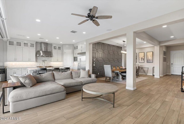 living room featuring light wood-type flooring, sink, and ceiling fan