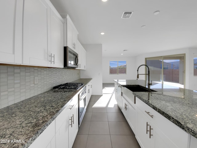 kitchen featuring dark stone counters, sink, white cabinets, and stainless steel appliances