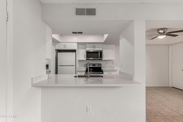 kitchen featuring kitchen peninsula, ceiling fan, light tile patterned flooring, white cabinetry, and stainless steel appliances