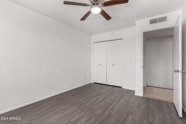 unfurnished bedroom with a textured ceiling, ceiling fan, a closet, and dark hardwood / wood-style floors