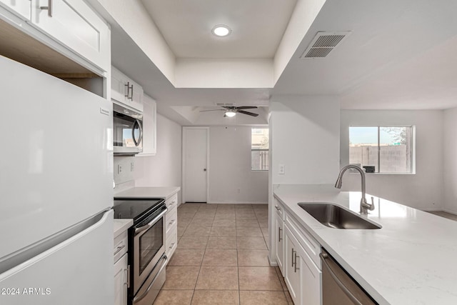 kitchen featuring ceiling fan, sink, light tile patterned floors, white cabinets, and appliances with stainless steel finishes