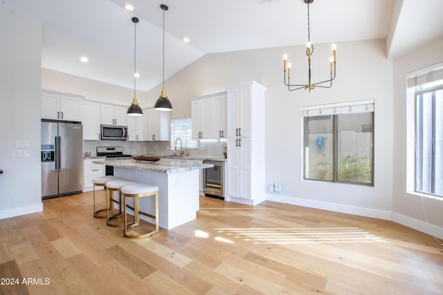 kitchen featuring white cabinets, pendant lighting, stainless steel appliances, and a kitchen island