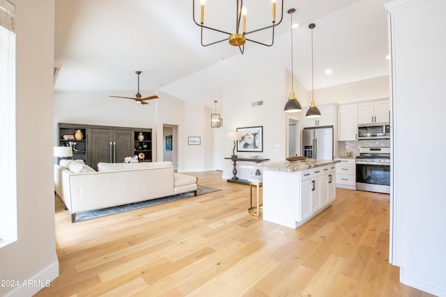 kitchen featuring a center island, backsplash, appliances with stainless steel finishes, decorative light fixtures, and white cabinetry