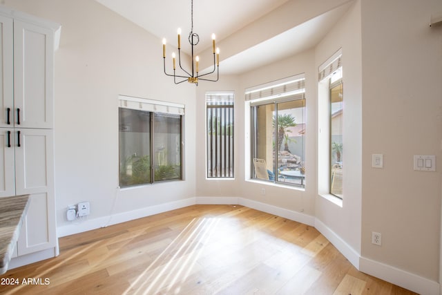 unfurnished dining area featuring light hardwood / wood-style floors and a notable chandelier