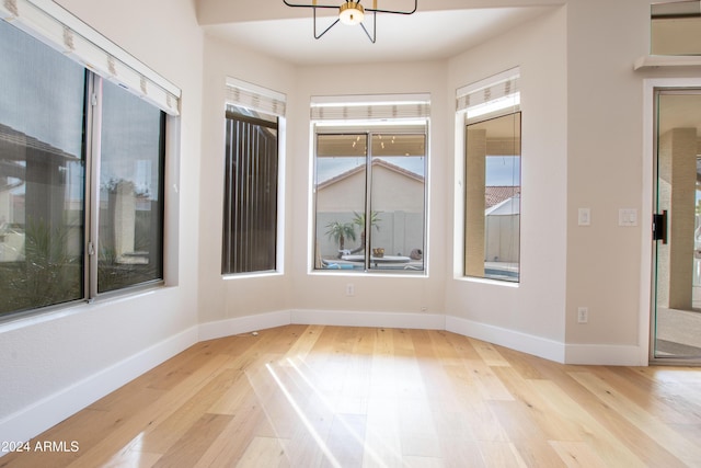 spare room featuring an inviting chandelier and light hardwood / wood-style flooring