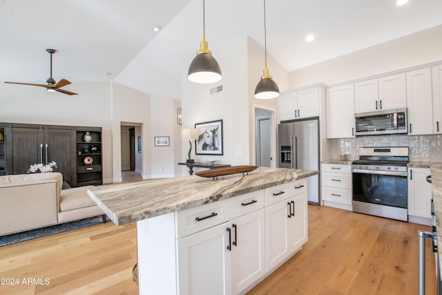 kitchen featuring a center island, hanging light fixtures, appliances with stainless steel finishes, tasteful backsplash, and white cabinetry