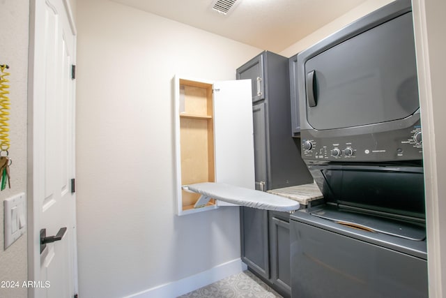 laundry room with cabinets and stacked washer and clothes dryer