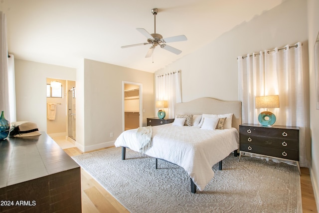 bedroom with ceiling fan, ensuite bathroom, hardwood / wood-style floors, a walk in closet, and a closet