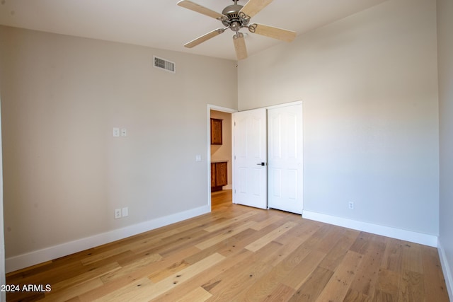 unfurnished bedroom featuring ceiling fan, light hardwood / wood-style floors, lofted ceiling, and a closet