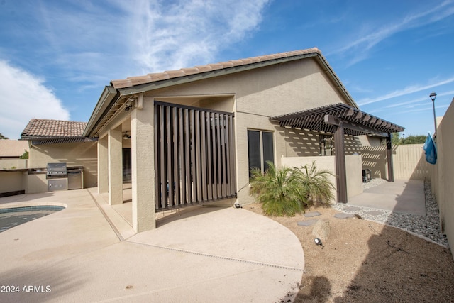 rear view of property with an outdoor kitchen, a pool, a pergola, and a patio